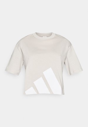 Orezáňované bežové tričko z bavlny s krátkymi rukávmi, s veľkým bielym geometrickým vzorom na dolnej ľavej strane. Okrúhly výstrih.