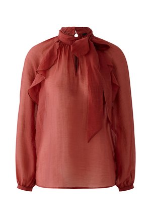 Blouse en voile rouille à manches longues avec épaules à volants et col noué en forme de nœud.