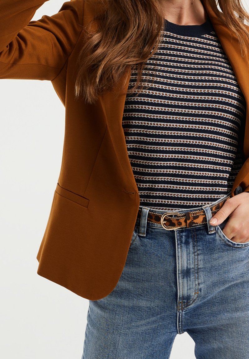 Brown blazer with a smooth texture, worn over a striped navy and white top, paired with light blue jeans and a leopard print belt.