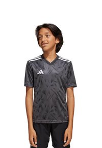 Graues, kurzärmliges Fußballtrikot mit einem strukturierten geometrischen Muster, drei weißen Streifen an den Schultern und einem V-Ausschnitt.