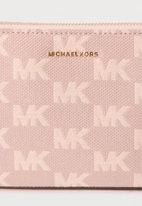 Carteira de tecido rosa com superfície texturizada, padrão de logótipo em relevo e ferragens em tom dourado, fecho de correr e bordas suaves.