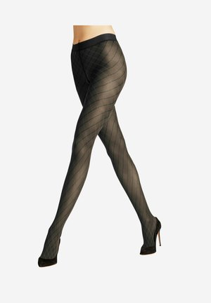 Beine mit schwarzen gemusterten transparenten Strumpfhosen und schwarzen High Heels, die sich vor einem schlichten weißen Hintergrund kreuzen.