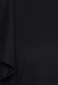 Czarny t-shirt o miękkiej, gładkiej fakturze. Charakteryzuje się luźnym krojem i krótkimi rękawami, ze prostymi detalami szwów.