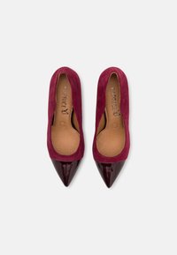 Escarpins bordeaux à bout pointu avec un bout de cap en bordeaux brillant contrastant. Fabriqués en daim souple avec une doublure intérieure lisse.