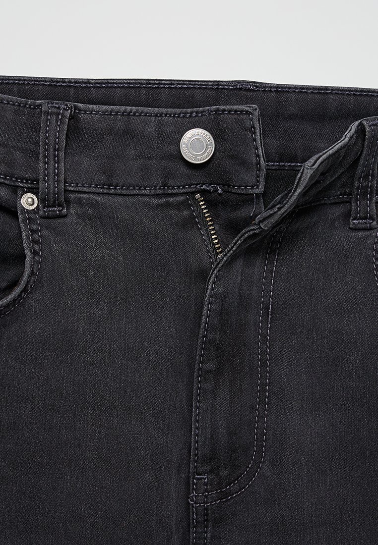 Zwarte spijkerbroek van denim met een rits en metalen knoopsluiting, en gestikte accenten. Kenmerken zijn onder andere voorzakken en een klassieke pasvorm.