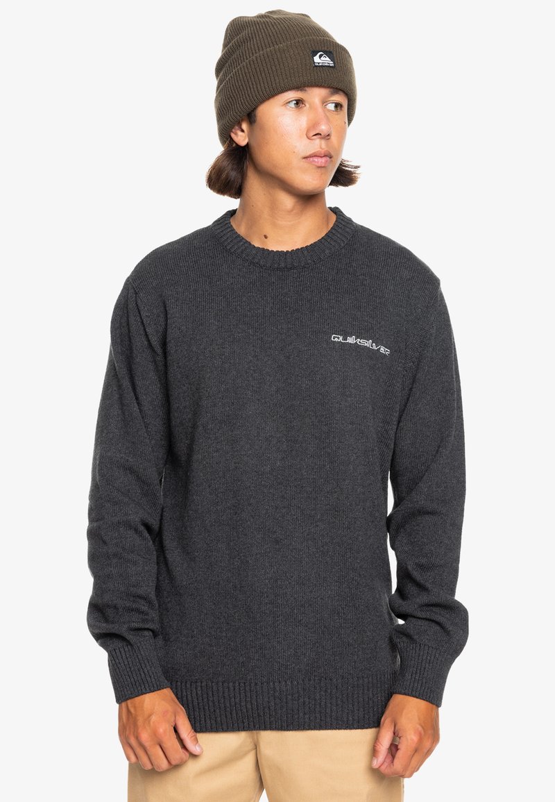 Kolgrå stickad tröja med ribbade muddar och fåll, med en liten vit logotyp på bröstet och en klassisk rund halsringning.