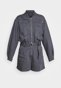 Mono de utilidad gris con mangas largas, cierre frontal, dos bolsillos en el pecho, cintura ceñida con cinturón y pantalones cortos. Fabricado en un tejido ligero.
