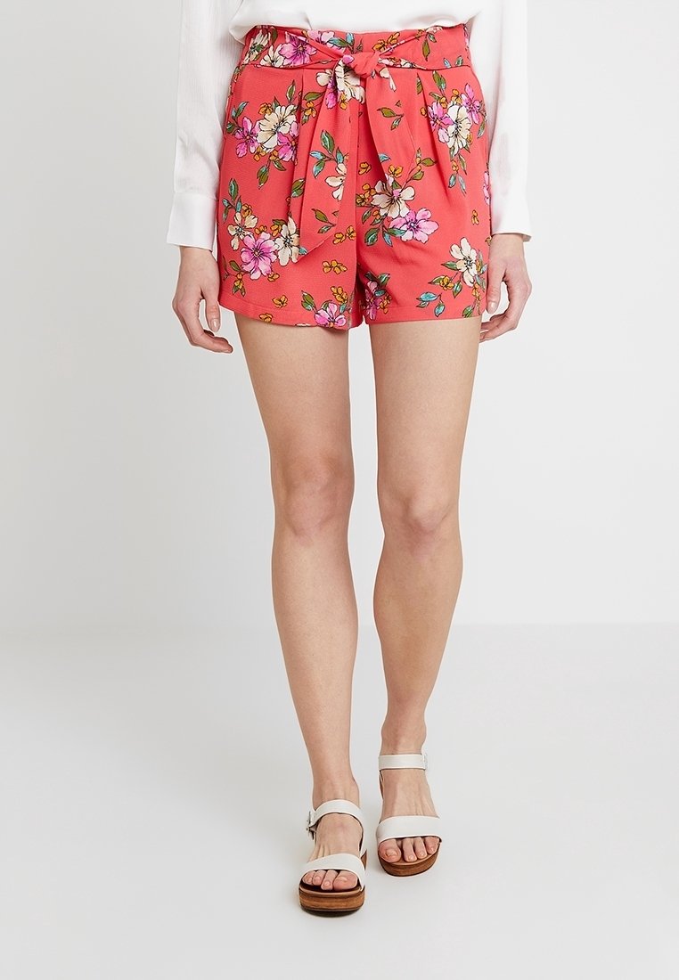 Pantaloni corti rossi con vita legata, caratterizzati da un vivace motivo floreale in rosa, bianco e verde. Realizzati in tessuto leggero.