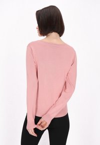 Roza pulover s dolgimi rokavi z mehko teksturo in rebrastimi manšetami. Ima širok izrez in sproščen kroj. Zadnji pogled razkriva gladke šive.