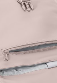 Világos rózsaszín hátizsák sima, matt textúrával. Két cipzáras rekesszel, ezüst hardware-rel és kontrasztos kék belső béléssel.