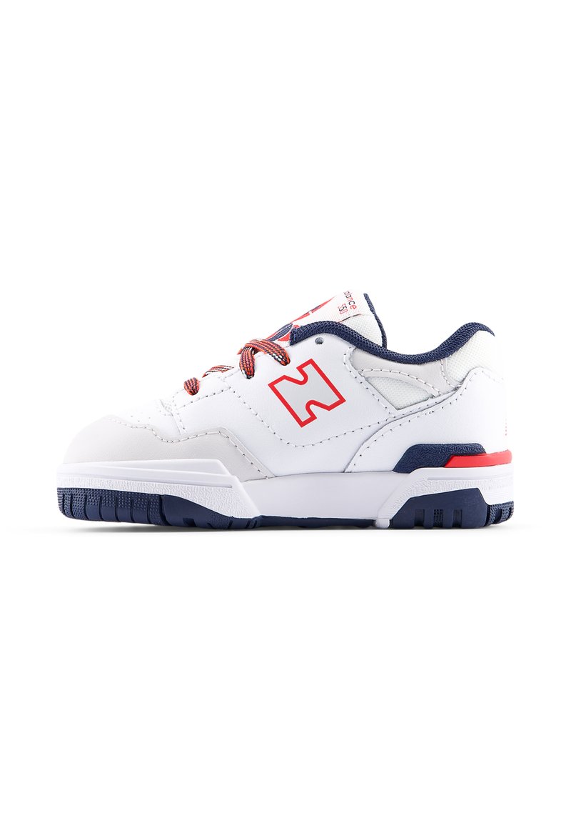 Zapatilla deportiva blanca con acentos rojos y marinos, que presenta un upper suave, suela texturizada y cordones en contraste. Logo en el costado.