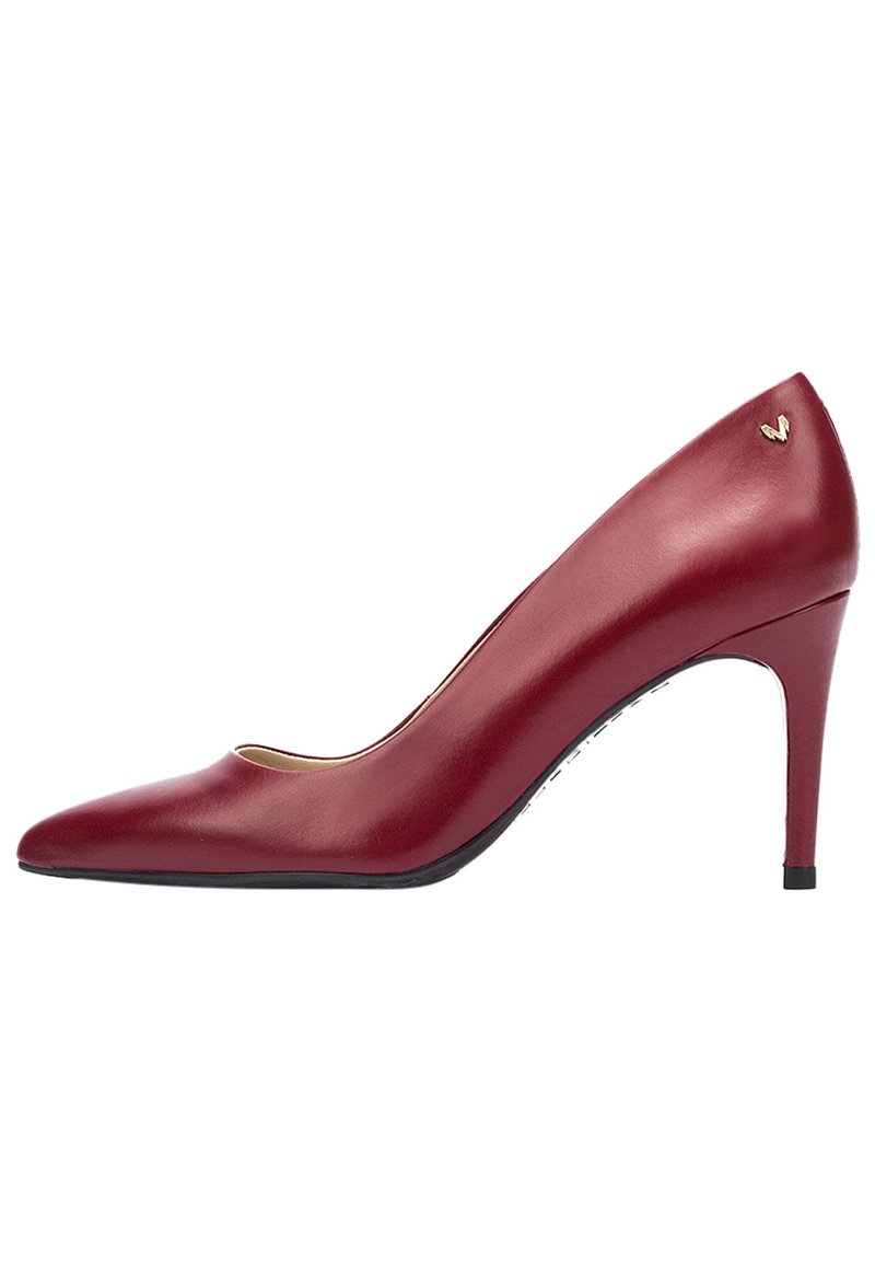 Zapato de tacón alto de cuero rojo con punta afilada, tacón delgado y un discreto detalle de marca en la parte posterior. Textura suave y diseño elegante.