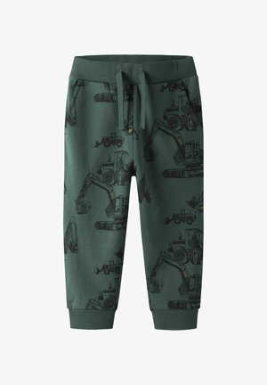 Pantalon de survêtement en coton vert avec un imprimé intégral de machines de chantier en noir. Taille élastique avec cordon de serrage et poignets côtelés.