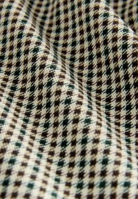 Textilstoff mit Hahnentrittmuster aus abwechselnden braunen und grünen Quadraten auf cremefarbenem Hintergrund, strukturierter Webart.