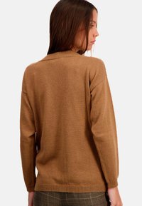 Pull en maille marron avec manches longues et ourlet côtelé. Texture douce et coupe décontractée. La vue arrière montre des coutures plates et un design simple.