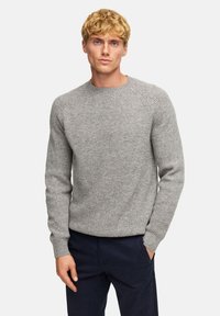 Grauer gestrickter Pullover mit Rundhalsausschnitt und gerippter Textur. Verfügt über lange Ärmel und eine lässige Passform, kombiniert mit navyblauen Hosen.