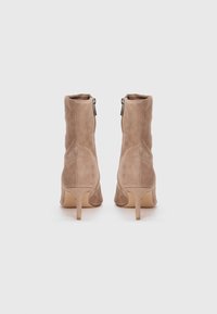 Tan suede ankle boots with a sleek design, pointed toe, and 2.5-inch stiletto heel. Features side zipper for easy wear.
