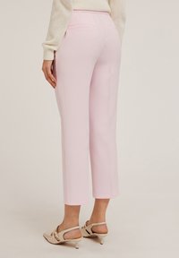 Lichtroze op maat gemaakte broek met een rechte pijp, voorzien van achterzakken en een gladde textuur, gecombineerd met beige slingback schoenen.
