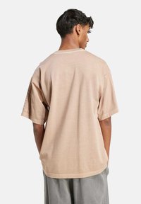 Beige oversized t-shirt with a crew neck and short sleeves. Soft, smooth texture with a relaxed fit. No visible patterns or embellishments.