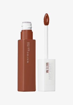 Rouge à lèvres liquide Maybelline Super Stay Matte Ink dans un contenant brun mat, avec un applicateur blanc et un embout en forme de pied de faon effilé.