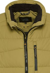 Olivengrüner, gepolsterter Jacke mit hohem Kragen, Reißverschluss und schwarzem Futter; verfügt über Kordelzüge und ein Markenschild im Inneren.