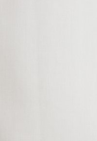 Weiße High-Top-Sneaker mit Schnurrbart- und Lippen-Print, getragen mit schwarz-rosa gestreiften Hosen auf gefliestem Boden.