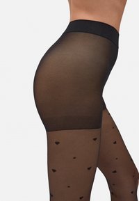 Medias negras semitranslúcidas con una cinturilla sólida, que presentan un patrón de pequeños corazones negros a lo largo de la sección de la pierna.