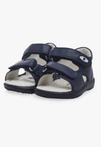 Sandales bleu marine avec deux sangles Velcro ajustables, design ouvert à l'avant et semelle intérieure rembourrée avec perforations pour la respirabilité.
