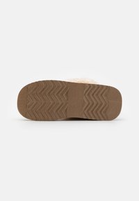 Suola in gomma marrone con motivo a zigzag e una parte superiore morbida e testurizzata, dotata di una fodera beige soffice per il comfort.
