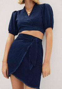 Mørkeblå denim to-delt sæt med en cropped omslagstop med puffede korte ærmer og en matchende omslagsnederdel med bindebælte.