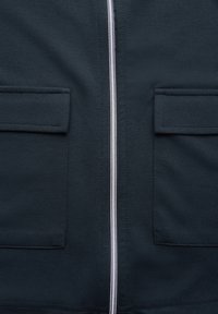 Giacca zip-up navy realizzata in tessuto morbido, con una cerniera frontale e due tasche applicate, con cuciture pulite e una finitura texturizzata.