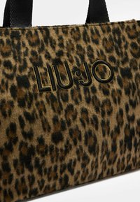 Tote taška z mäkkého tkaného materiálu s leopardím vzorom a čiernym vyšitým názvom značky "LIU•JO", vybavená pevným čiernym uchom a textúrovaným povrchom.
