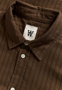 Bruine overhemd met knopen en een verticale streepjespatroon, met een puntig kraag, witte knopen en een label met een wit logo.