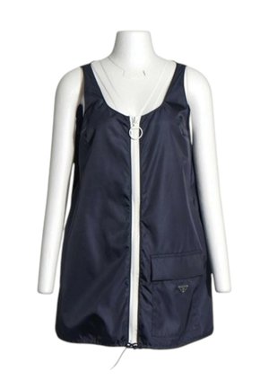 Vestido azul marino sin mangas con cremallera blanca delante y bolsillo en el lado derecho, mostrado en torso de maniquí blanco sobre fondo blanco.