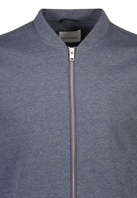 Granatowa kurtka typu bomber z kołnierzem typu stójka, wyposażona w pełny srebrny zamek błyskawiczny i teksturowaną tkaninę. Wewnątrz kołnierza znajduje się metka z napisem "Lindbergh".