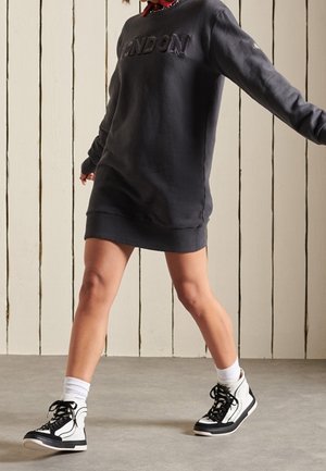 Vestido sudadera gris oscuro con "LONDRES" en letras en relieve, combinado con zapatillas altas en blanco y negro y calcetines blancos hasta el tobillo.