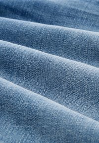 Plavi denim s teksturiranim tkanjem, prikazuje nježne nabore i ravnu površinu s suptilnom varijacijom boje.