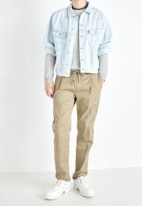 Light blue denim jacket, gray ribbed sweater, beige drawstring pants, and white chunky-soled shoes. Casual outfit with layered textures.