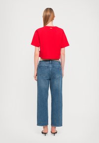 Un tricou roșu scurt, asortat cu blugi din denim albastri, cu talie înaltă. Blugii au o croială lejeră, cu un design clasic cu cinci buzunare și o spălare ușoară.