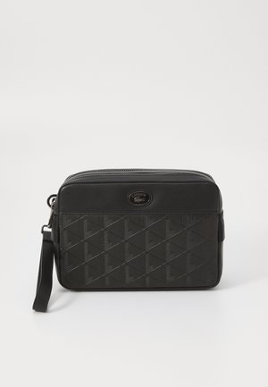 Bolso cruzado sintético negro con patrón geométrico en relieve, cierre con cremallera y correa desmontable. Presenta un acento de logotipo de la marca.