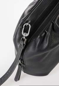Borsa in pelle nera con superficie testurizzata, forma arrotondata, parte superiore increspata, chiusura con zip, accessori in metallo e tracolla staccabile.