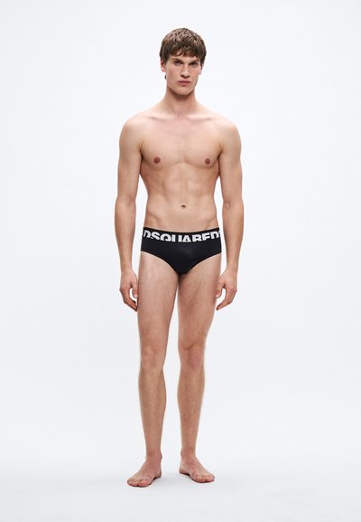 Μαύρο εσώρουχο τύπου μπόξερ με φαρδιά ελαστική μέση που φέρει λευκό κείμενο λογότυπου. Λείο, εφαρμοστό σχέδιο με ελάχιστη κάλυψη.