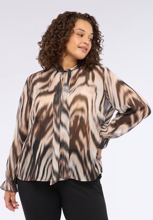 Blusa transparente con un patrón abstracto en marrón y beige, que presenta un cuello con lazo, mangas largas y puños fruncidos. Material ligero.