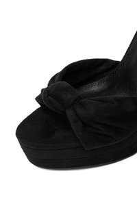 Černé sametové platformové boty s kulatou špičkou a mašlí na svršku. Mají texturovaný povrch a pevnou černou podešev.