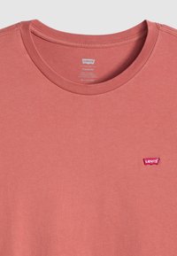 Korte mouwen crew neck t-shirt in koraal, gemaakt van katoen. Heeft een klein rood Levi's logo patch op de borst en een geribbelde halslijn.