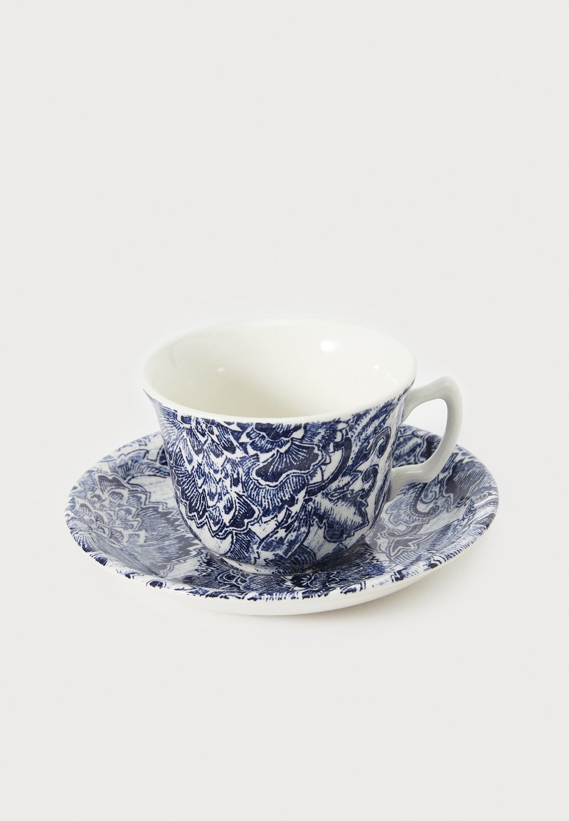 Set van keramische kop en schotel met ingewikkelde blauwe bloemenpatronen op een witte achtergrond; gebogen kopvorm met een handvat, gladde textuur.