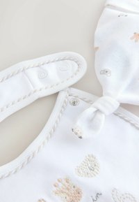 White cotton romper with snap fasteners, featuring soft embroidered animal designs in pale pink and gray. Matching patterned headband included.