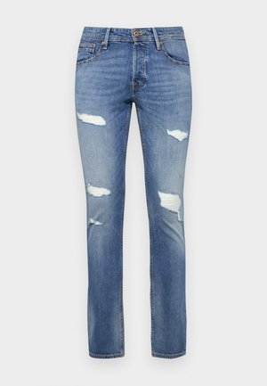 Jean en denim bleu avec une finition légèrement délavée, présentant plusieurs déchirures usées et un design à jambe droite. Fermeture à bouton à la taille.