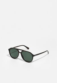 Ochelari de soare negri și cu model țiglă, cu lentile verzi, de formă rotundă și cadru din plastic ușor. Au brațe subțiri cu marcaj.