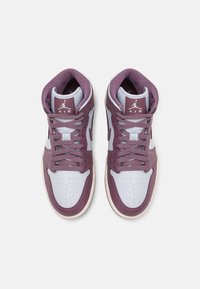 Paire de baskets montantes avec panneaux blancs et mauves, coque perforée, lacets mauves et logo Air Jordan sur les languettes, vue de dessus.